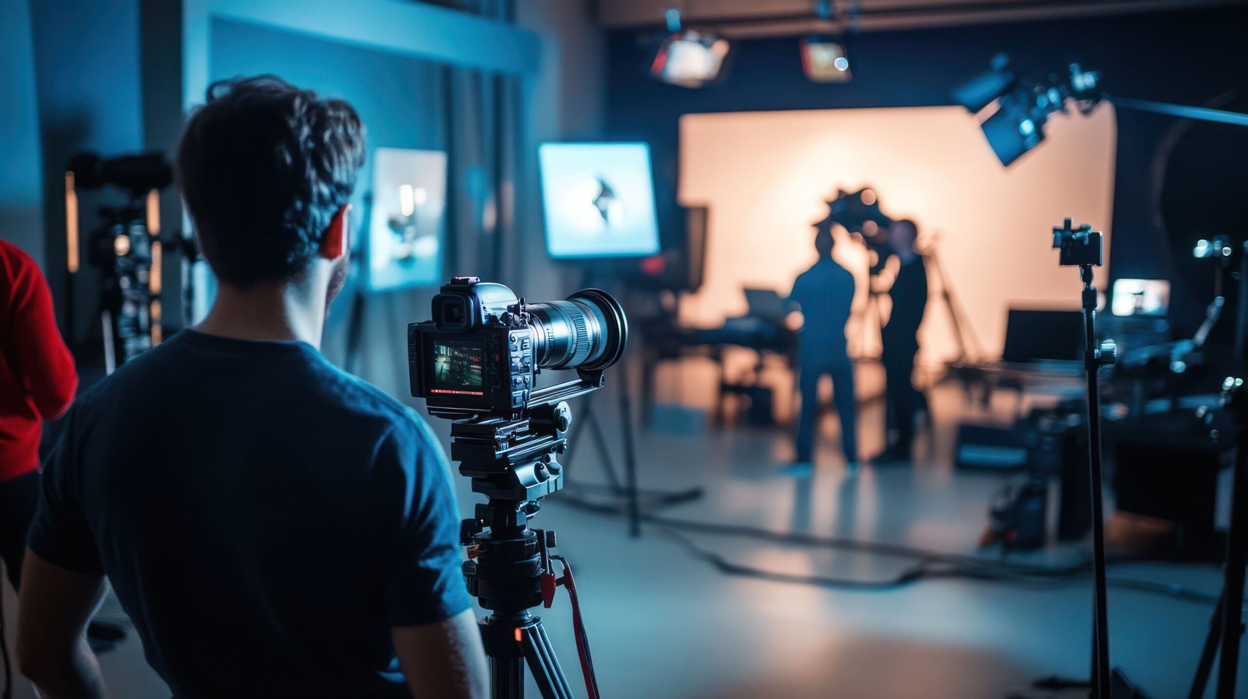 Kameramann im Studio koordiniert ein Videoprojekt mit Team im Hintergrund